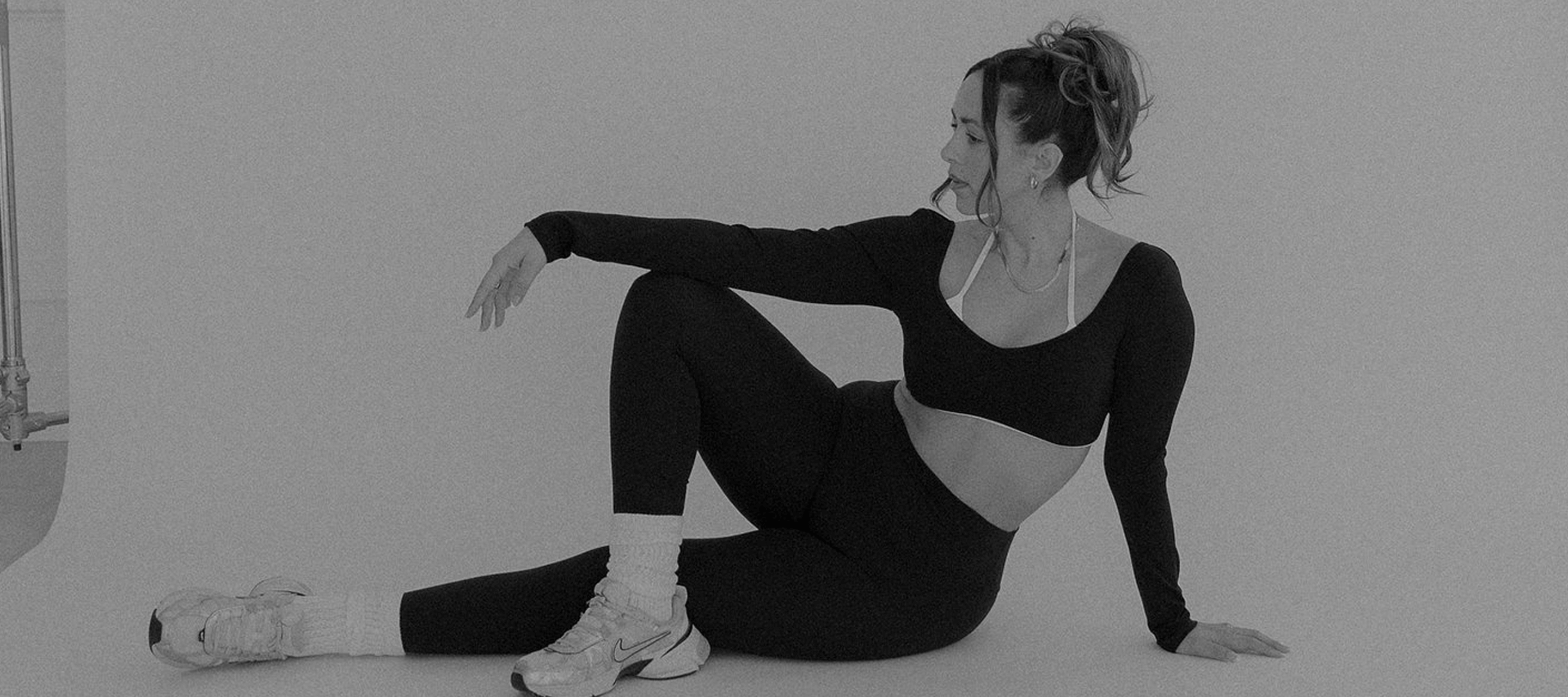 Black and white image of a woman sitting in her trendy workout clothes after taking a FITclub workout class.